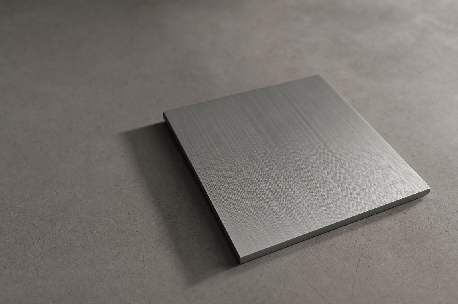 A brushed aluminium plate with fine parallel grooves under raking light